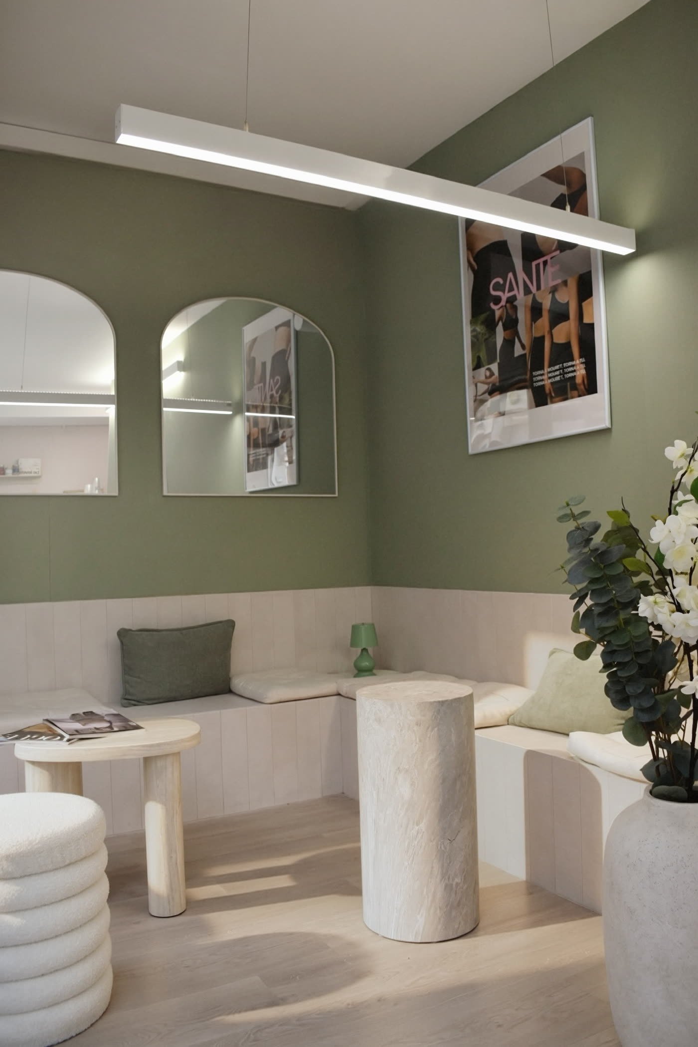 La recepción de Santé, con la pared verde salvia y los espejos en arco